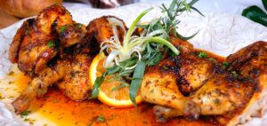 Close up of chicken dish with orange glaze and decorative garnish.